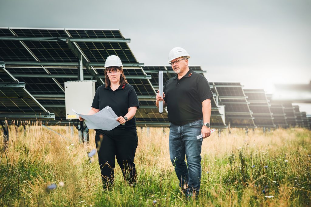 Zwei Personen vor Solarpaneelen zeigen erneuerbare Technik bei sonnigem Wetter draußen
