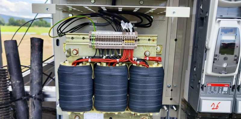 Nahaufnahme eines elektrischen Transformators mit Kabelanschlüssen.