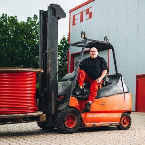 Konrad Karl fährt einen Gabelstapler mit roter Kabelrolle vor dem ETS-Gebäude